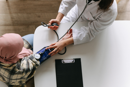 Care provider performing blood pressure screening on patient